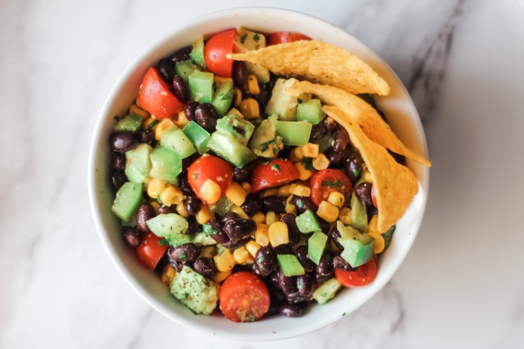 black bean corn salad win a white bowl garnished with tortilla chips
