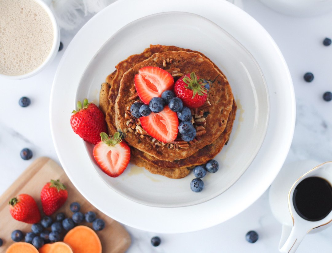 healthy plate of a stack of pancakes with strawberries, blueberries, sweet potato, whole wheat on a white plate