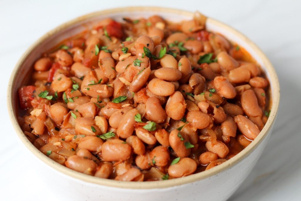 Mexican pinto beans in a white bowl garnished with cilantro