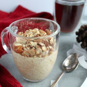 eggnog oatmeal on a table with a pinecone, a red towel, and coffee in the background