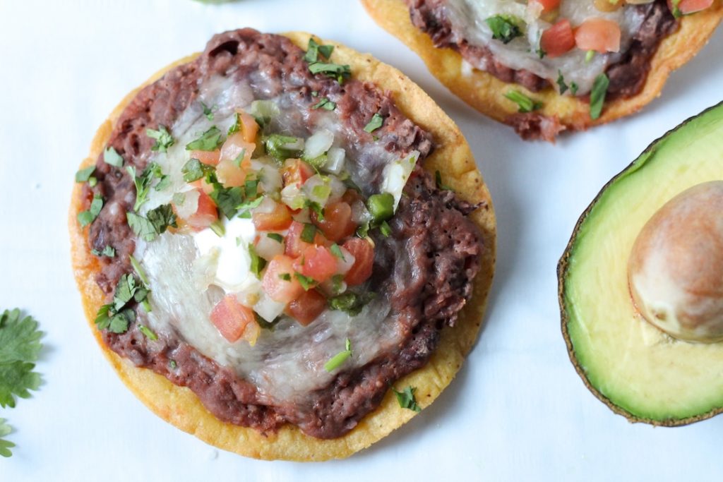 Bean and Cheese Tostadas with half an avocado