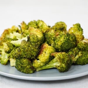 crispy roasted broccoli in a pile on a light blue plate