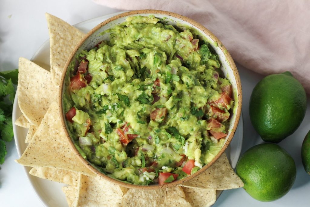 basic guacamole recipe in a bowl surrounded by corn chips