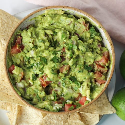 basic guacamole recipe in a bowl surrounded by corn chips