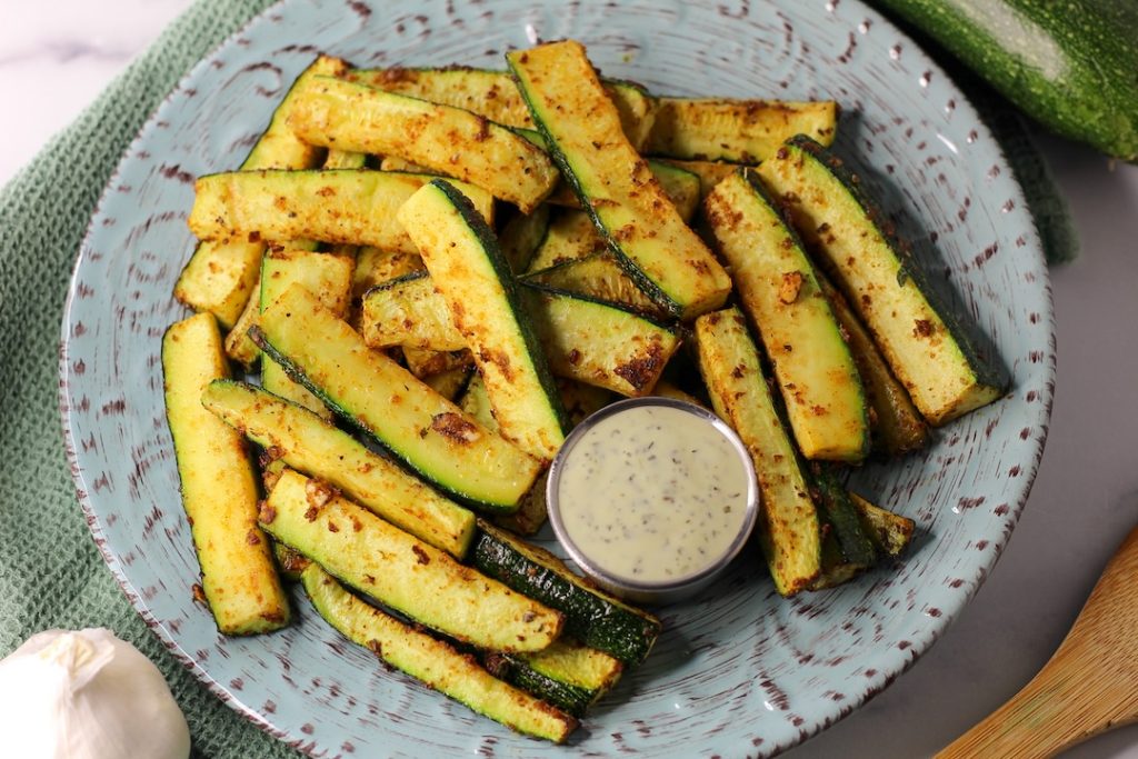 roasted spicy zucchini wedges on a plate with dip