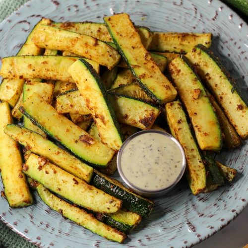 roasted spicy zucchini wedges on a plate with dip