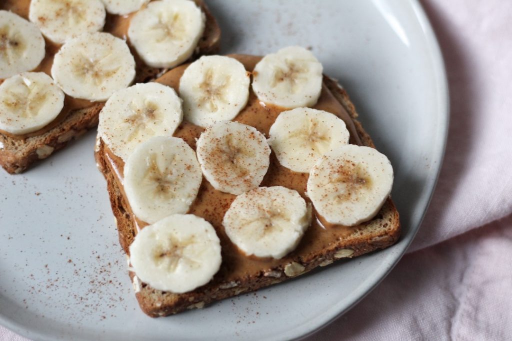 2 slices of peanut butter banana toast with cinnamon on a plate