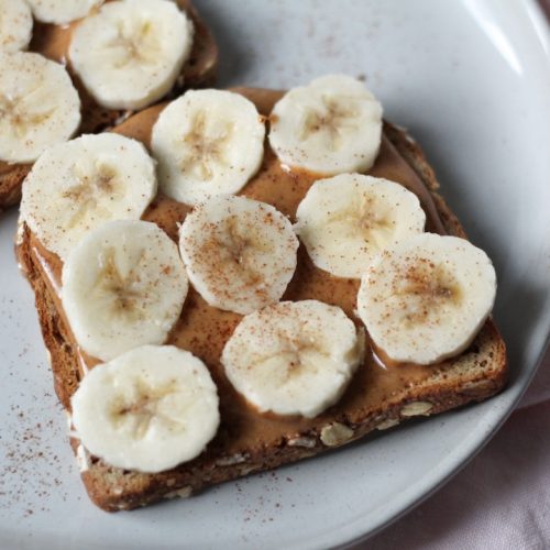2 slices of peanut butter banana toast with cinnamon on a plate