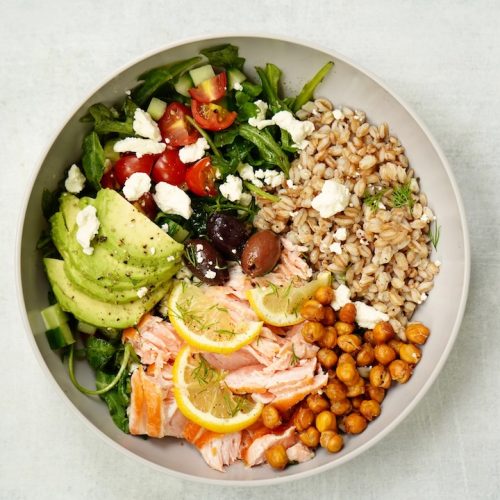 Mediterranean Salmon Salad Bowl with salmon, arugula, tomatoes, avocado, farro, roasted chickpeas, olives, feta cheese, and dill