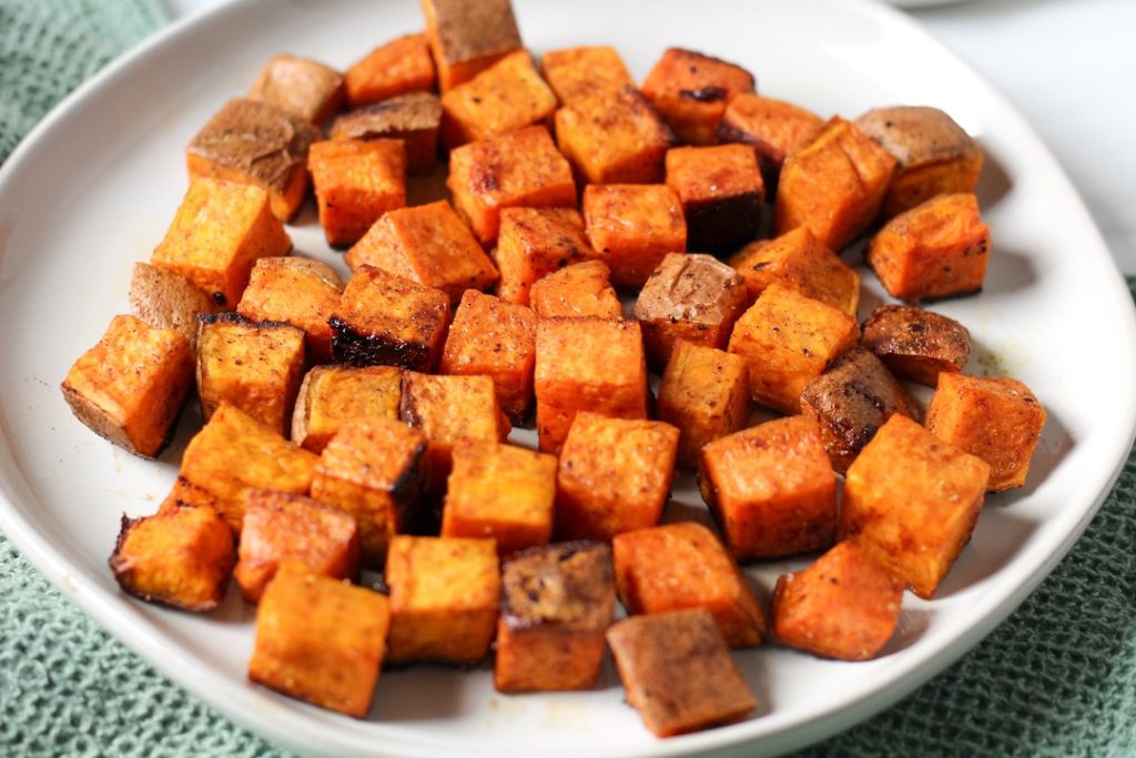 Roasted diced sweet potatoes with brown sugar on a white plate