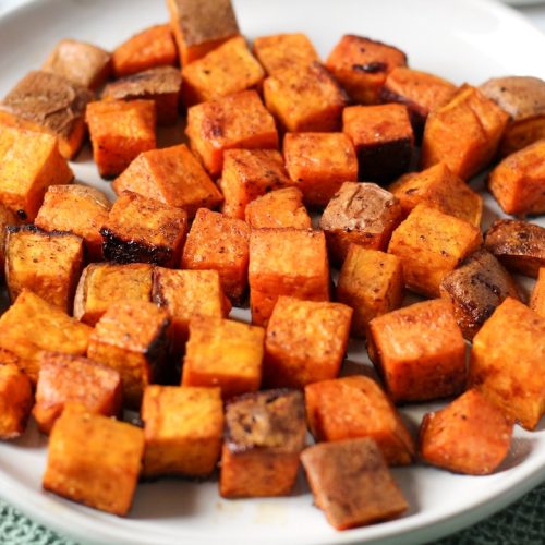Roasted diced sweet potatoes with brown sugar on a white plate