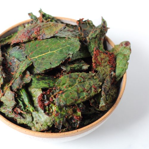 Spicy kale chips in a ceramic white bowl with a beige rim