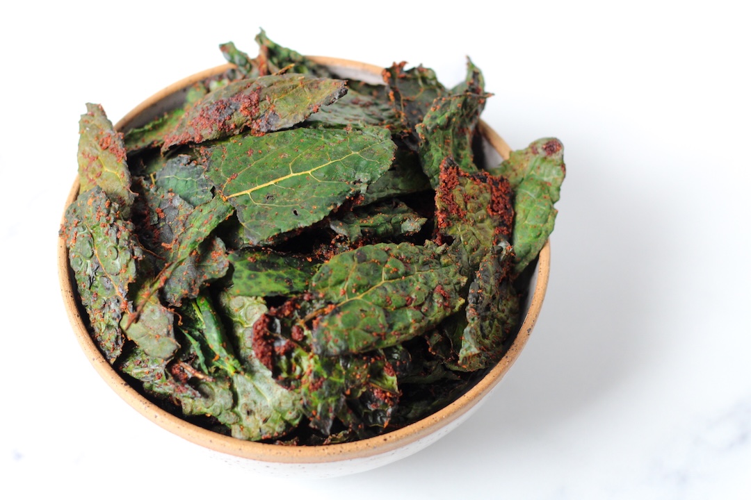 Spicy kale chips in a ceramic white bowl with a beige rim
